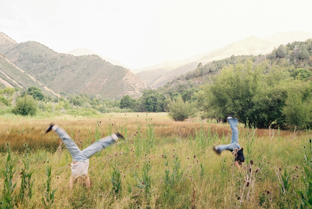Two people are doing cartwheels in a field.